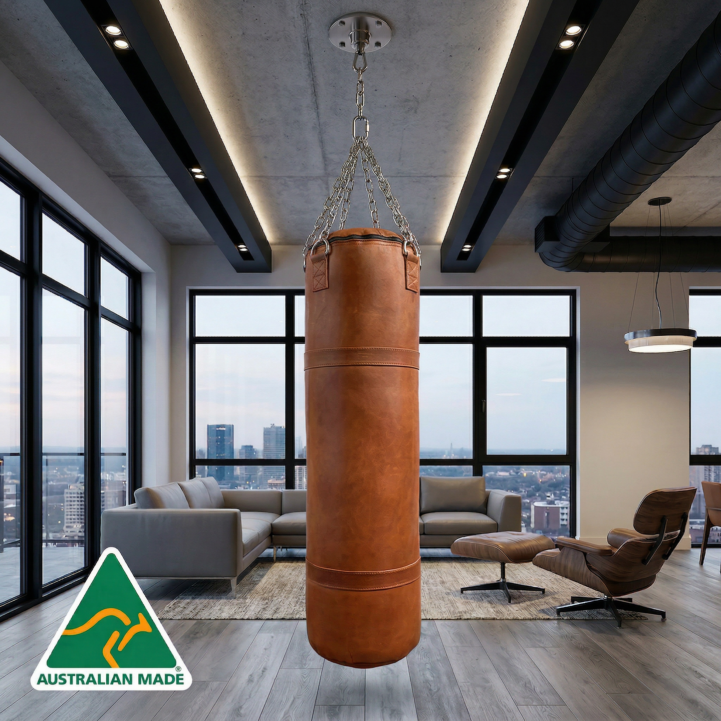 Brown leather punching bag hanging in a modern living room with large windows and cityscape view.
